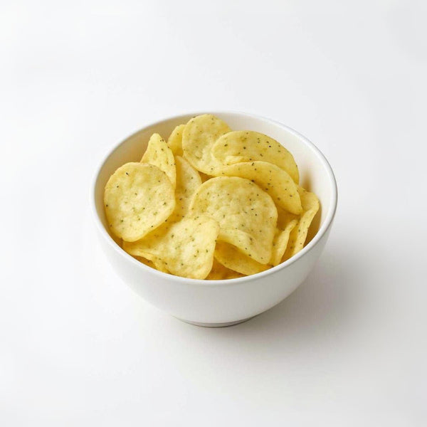 White bowl filled with yellow potato chips on a white background